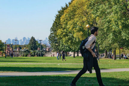 A male student walking outside in the college campus