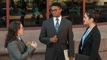 Three students talking outside in the college