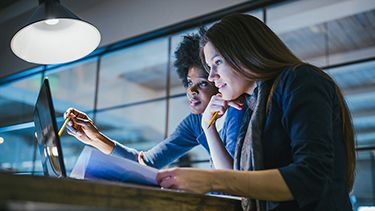 Two female students watching on the laptop screen