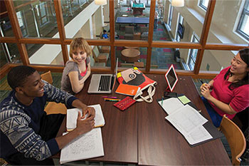 Three student talking and smiling in the library