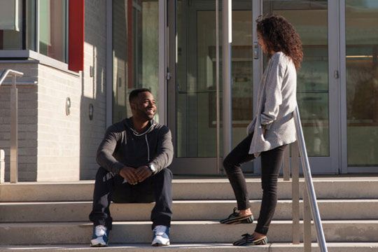 Male and female students talking on the stairs