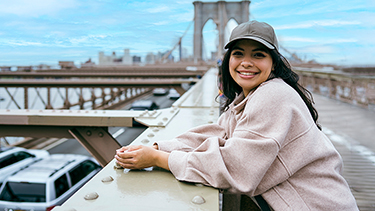 Female student smiling and standing on the bridge