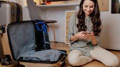 A female student packing clothes and watching on mobile