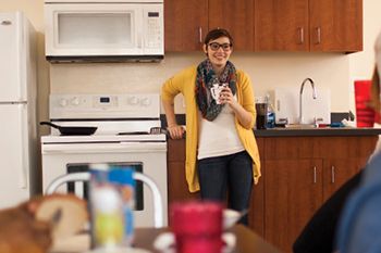 Student standing with a cup of coffee in the kitchen